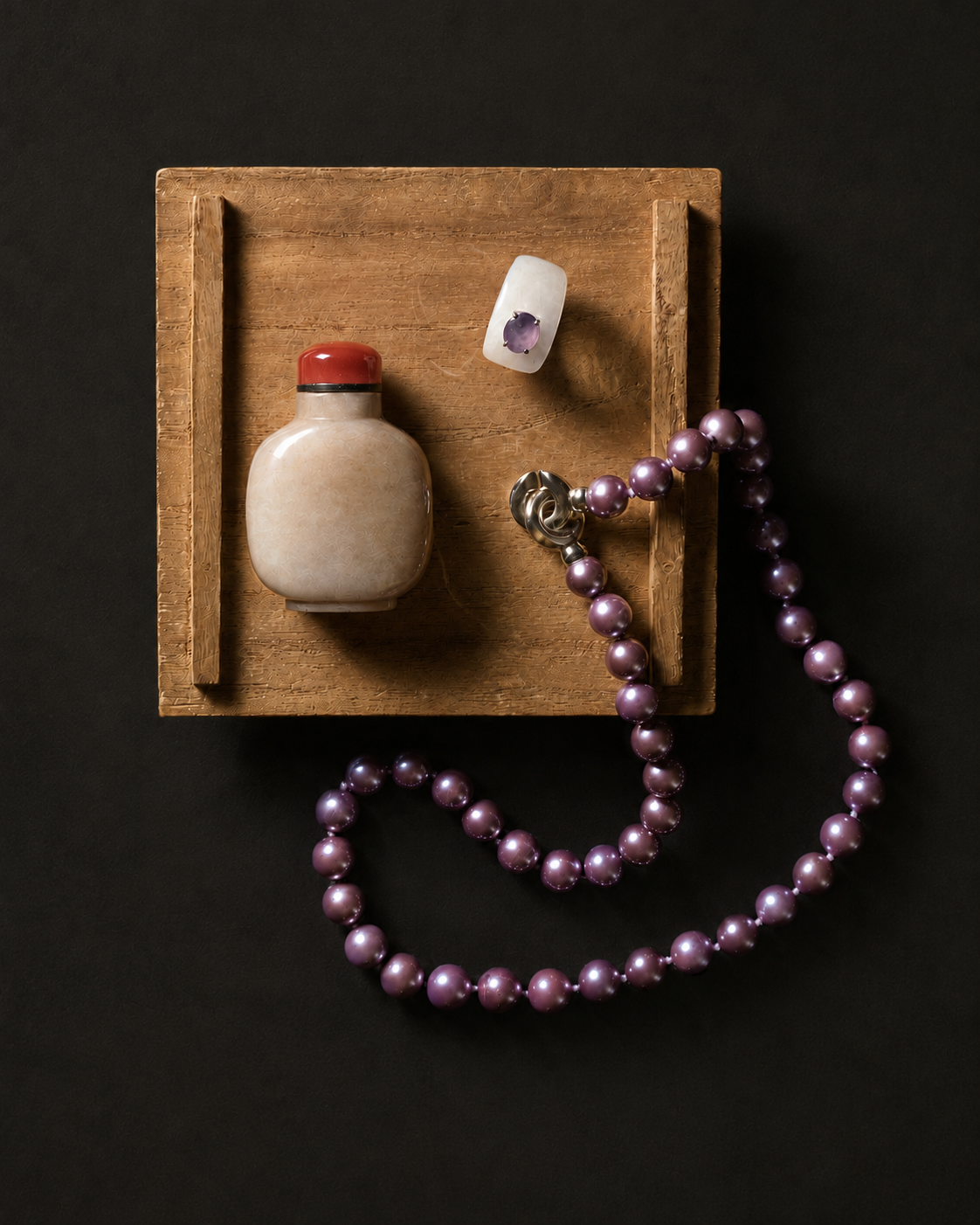 Snuff bottle, ring, and pearl necklace on a wood tray